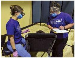 Foto de la asistente dental Lizz Rodríguez y la Dra. Alyssa Gruba hablando con un participante durante una evaluación